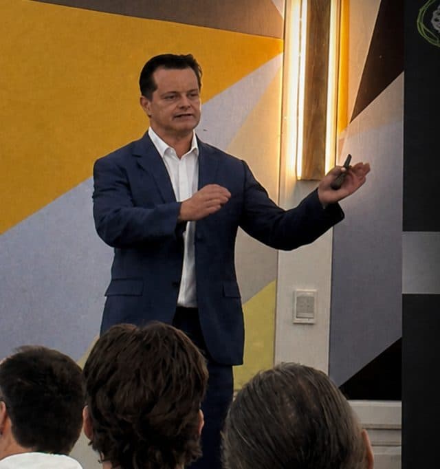 Greg Cassar presenting on stage at New Era Summit, Gold Coast